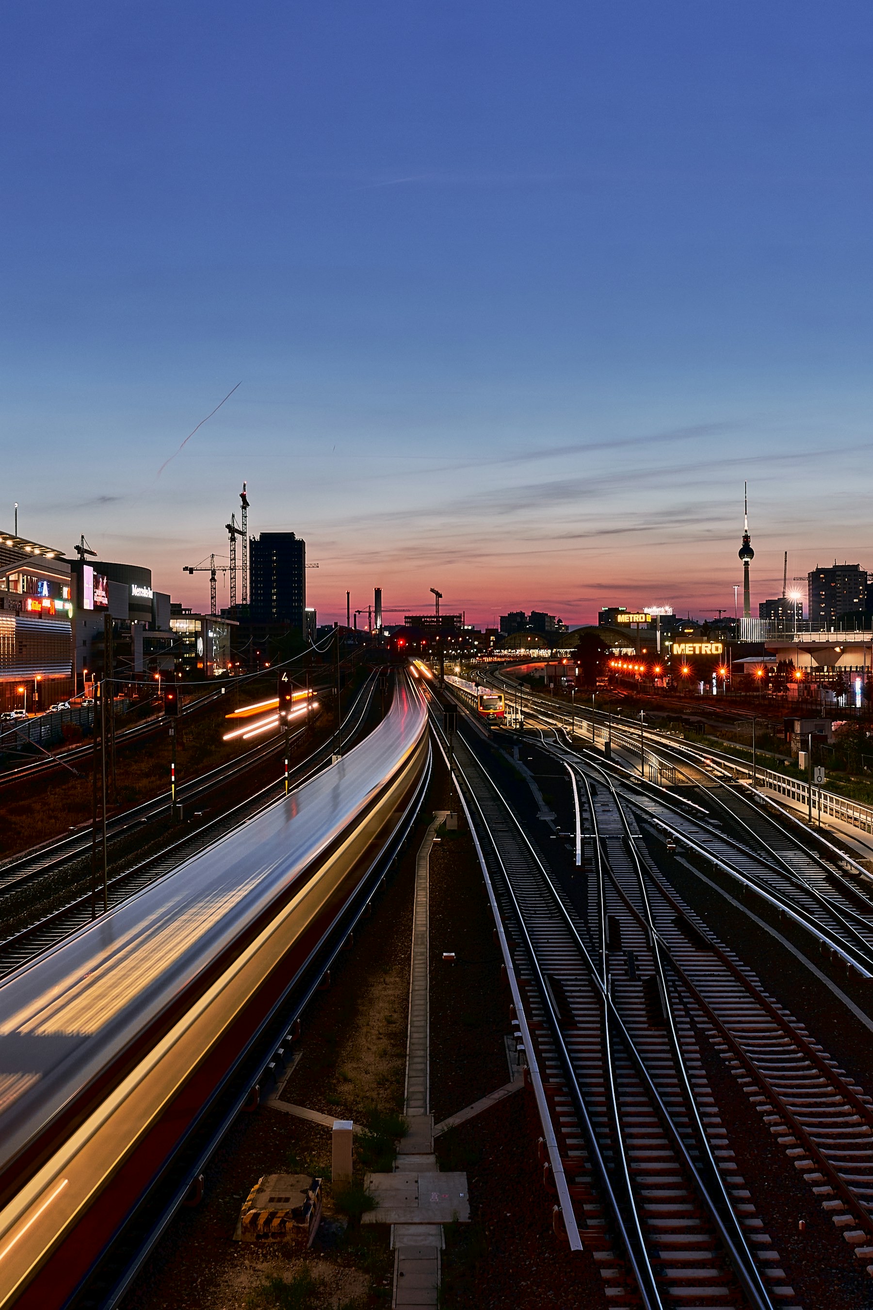 Railway tracks and a passing train at dusk. Photo from Unsplash.